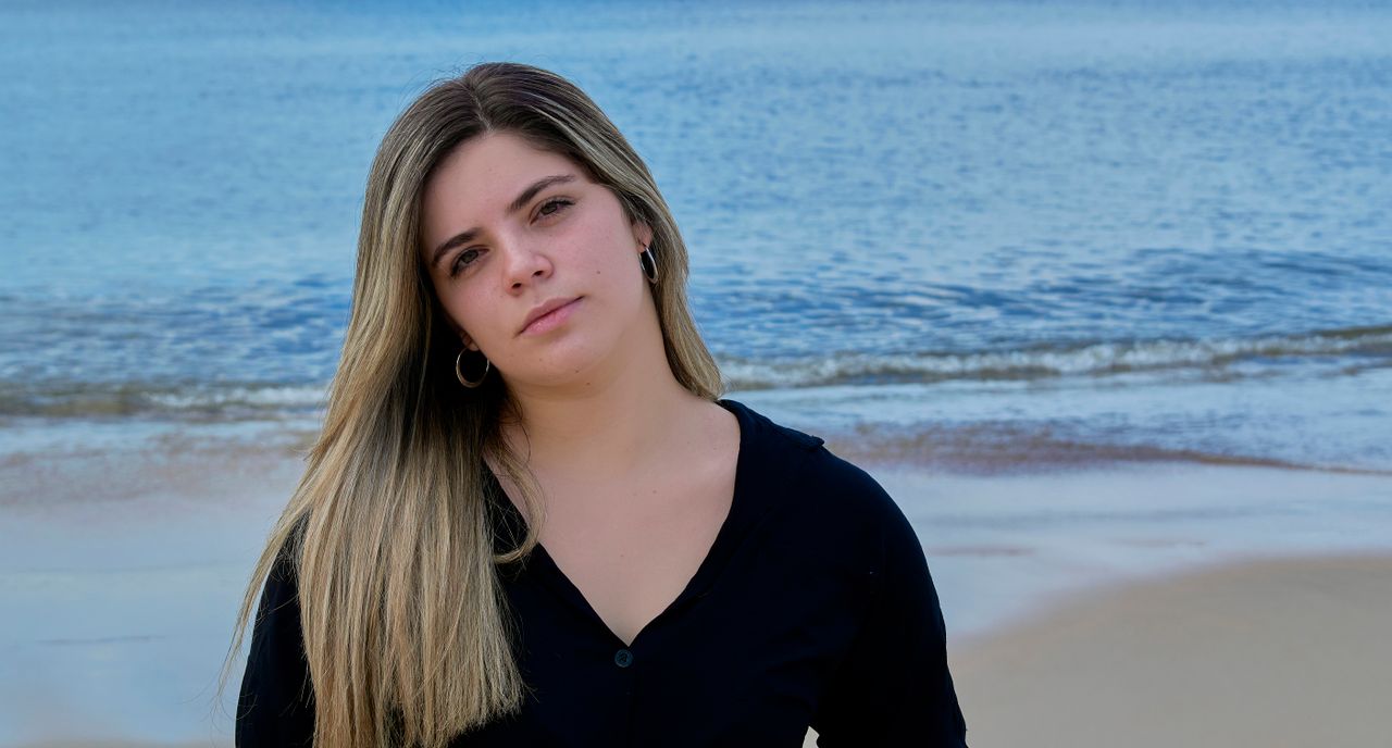 A serene portrait of a young woman on a quiet Uruguayan beach, with calm ocean waves.